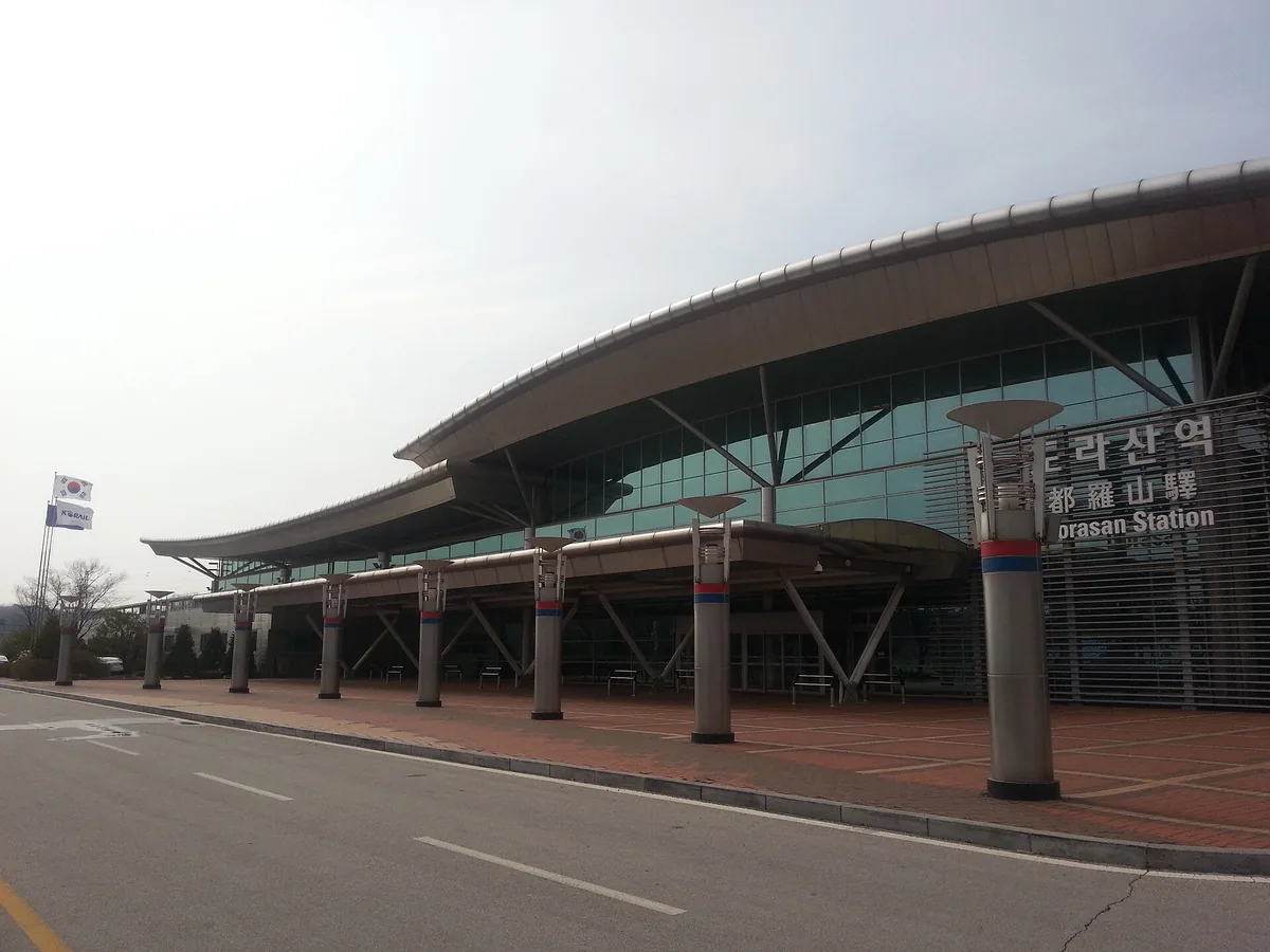 Modern railway station with a sweeping curved roof and colonnade above an empty forecourt