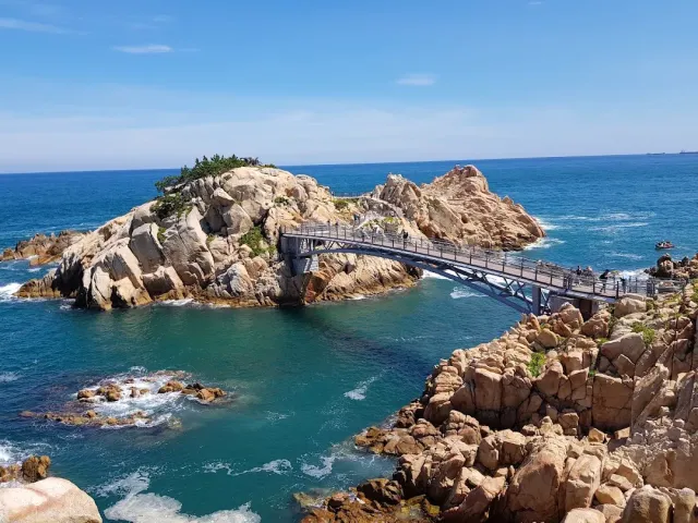 A metal footbridge to a pale rocky outcrop surrounded by turquoise water