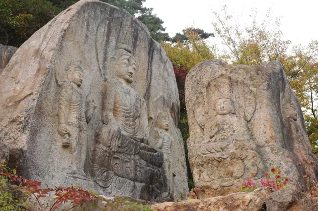 A Buddha figure carved into a large boulder on a forested slope