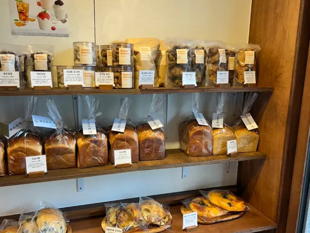Wooden shelves loaded with packaged loaves of bread, cookie jars and price labels
