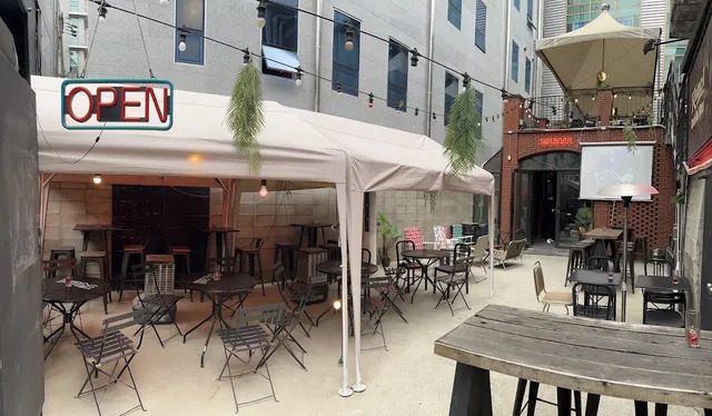 An inner courtyard with a white canopy, metal tables and a lit red open sign