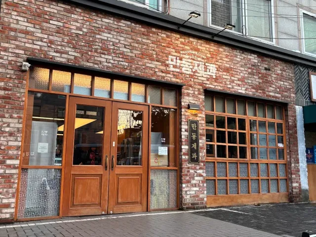A brick front with double wooden doors, windows in wooden frames and a small sign