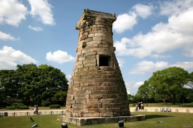A low round stone tower standing on a lawn under blue skies