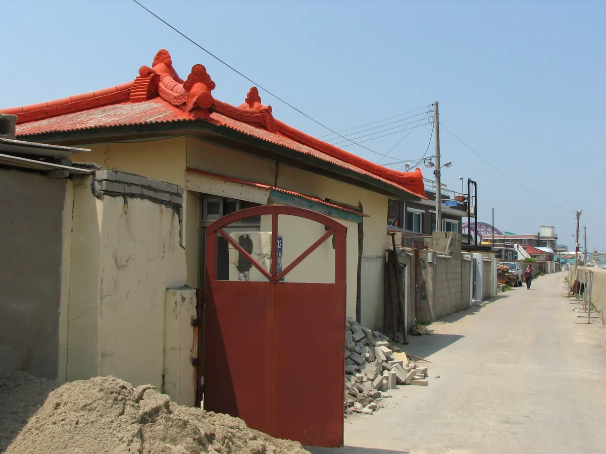 A lane in Abai Village in Sokcho, with a red gate and a tiled roof