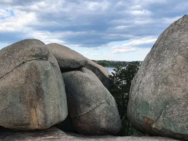 Huge rounded rock boulders, with a lake and houses visible between two of them