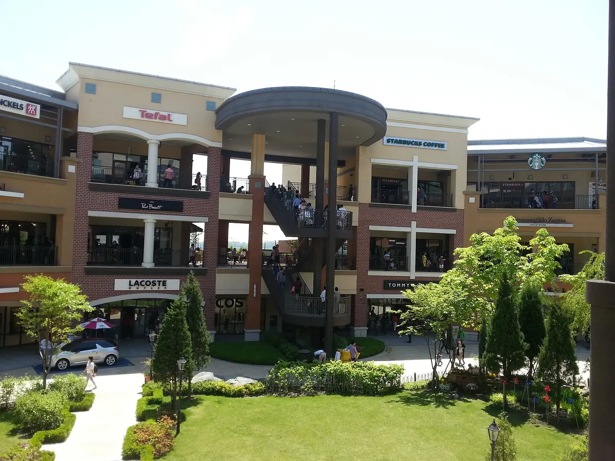 Open air outlet centre of three brick faced storeys with a spiral staircase and a planted lawn in front