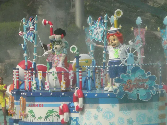 A colourful parade float with cartoon figures and water jets