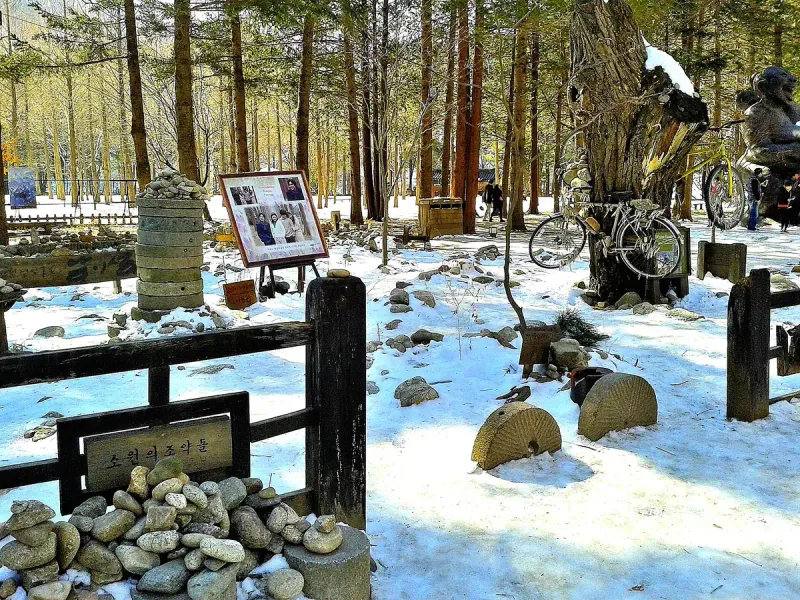 Snow covered memorial corner with bicycles and bare trees on Nami Island