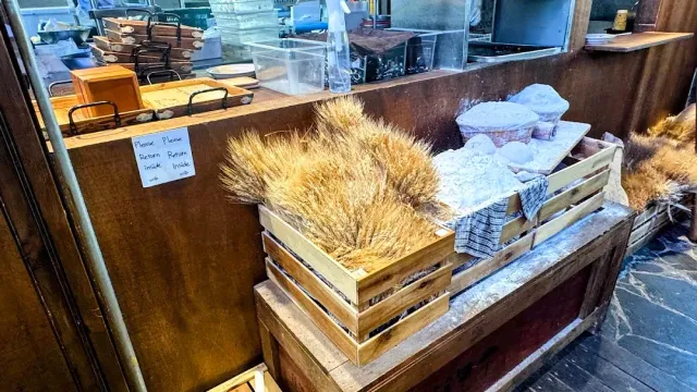 Wooden crates with wheat sheaves on a floured counter, with baking trays behind them