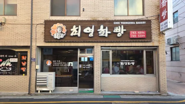A front with a brown sign and an illustration of a baker, a display window with workers behind it