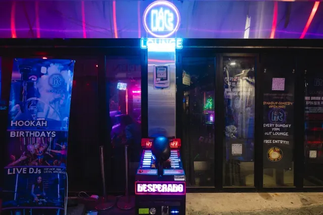 A front in the evening under purple neon light with a lit sign, banners and an arcade machine at the entrance
