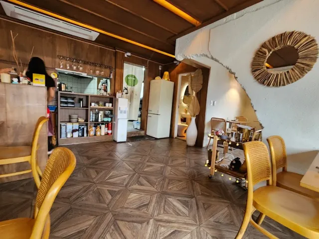 A space with wooden walls, a diamond parquet floor, shelves of tableware and a round reed mirror