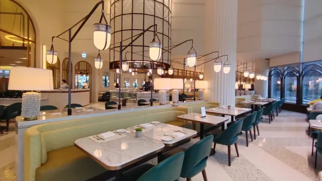 An elegant hall with marble tables, turquoise armchairs and hanging lantern lamps