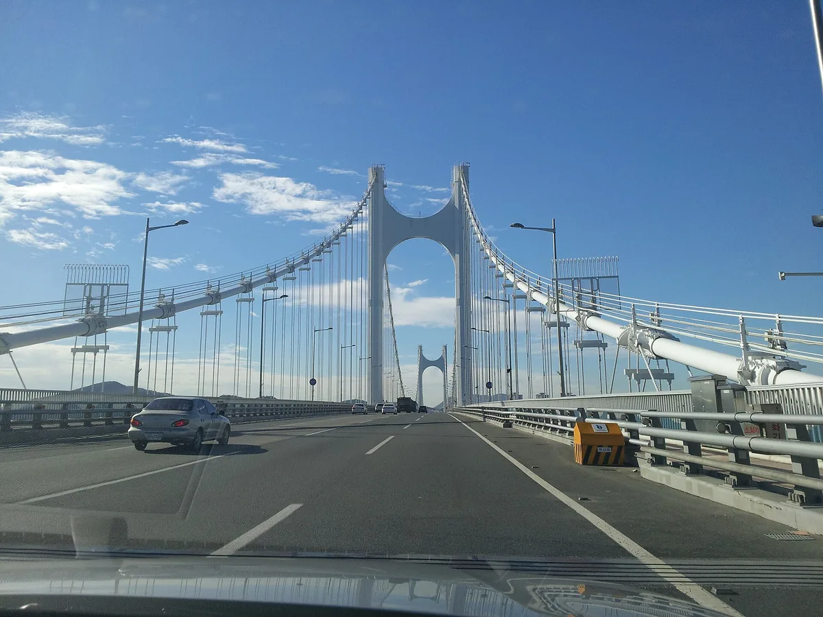 Driving across the suspension bridge over the bay in Busan with the white bridge tower ahead