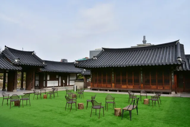 Tiled roof hanok houses around a green lawn set with tables