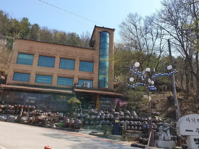 A three story building up a hill with hundreds of clay jars arranged in front of it