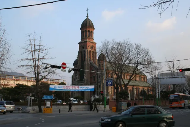 A red brick church with a tall bell tower on a street corner