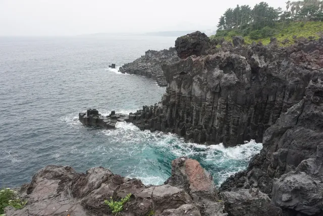 Basalt cliffs grooved into upright columns facing breaking waves