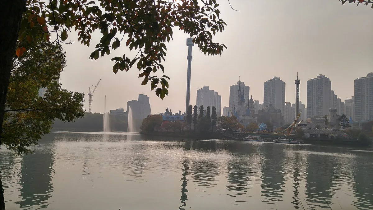 A city lake ringed with trees, apartment towers and the Seoul skyline behind