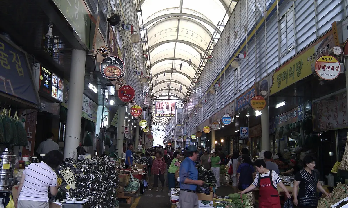 A busy covered market passage lined with stalls and goods on both sides