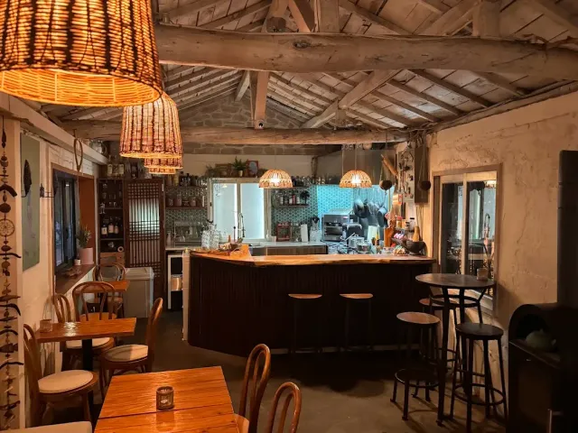 A room with exposed wooden beams, hanging rattan lamps and a counter with stools