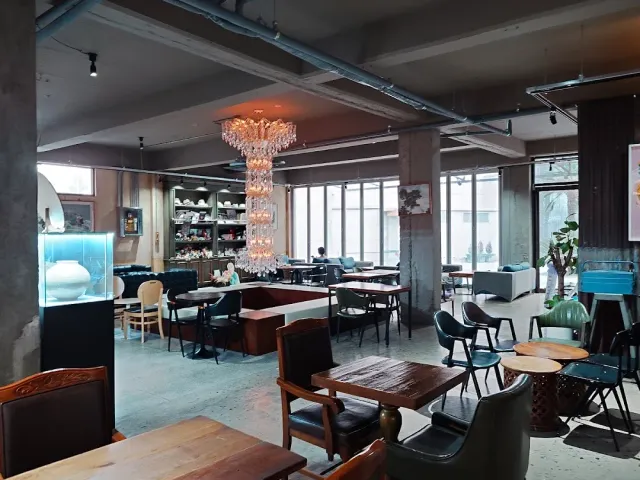 An industrial space with concrete columns, a large crystal chandelier and furniture in mixed styles