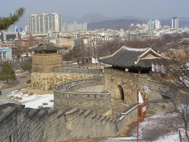 A stone fortress wall and guard pavilion above the city rooftops