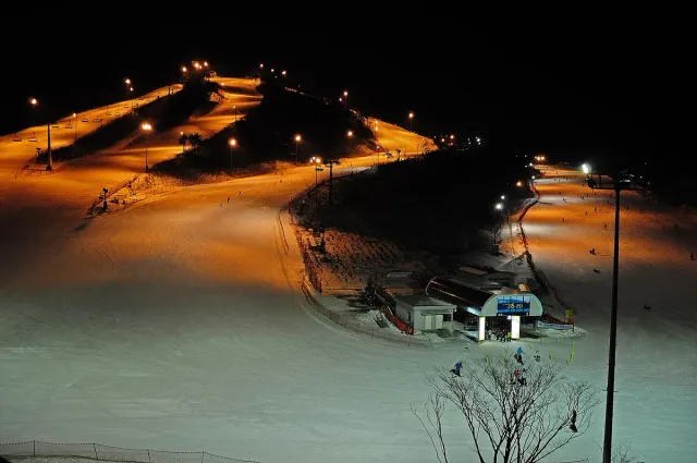 Floodlit ski runs on a mountainside at night