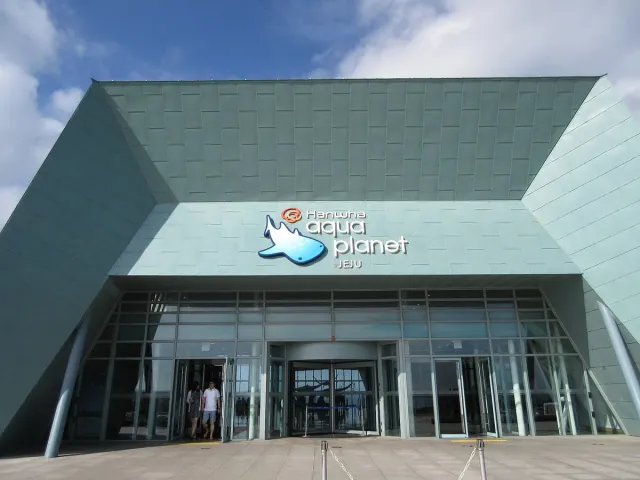The glazed front of a large aquarium building under blue skies