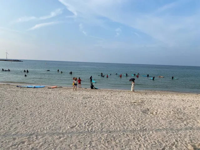 Shallow turquoise water and bathers on pale sand under bright skies