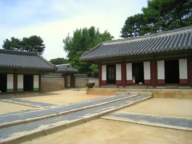 A low tiled roof shrine building above a wide empty stone courtyard