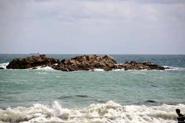 Dark rocks breaking the surface among crashing waves close to shore