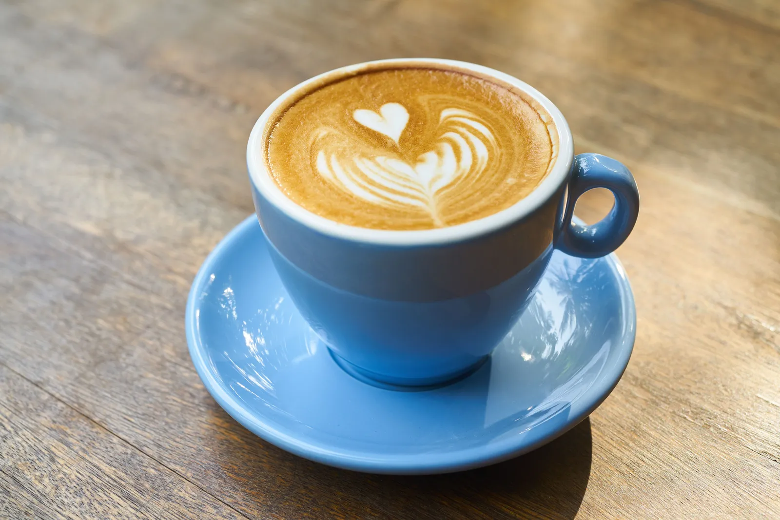 A cappuccino with latte art in a blue cup on a wooden table in Seoul, South Korea