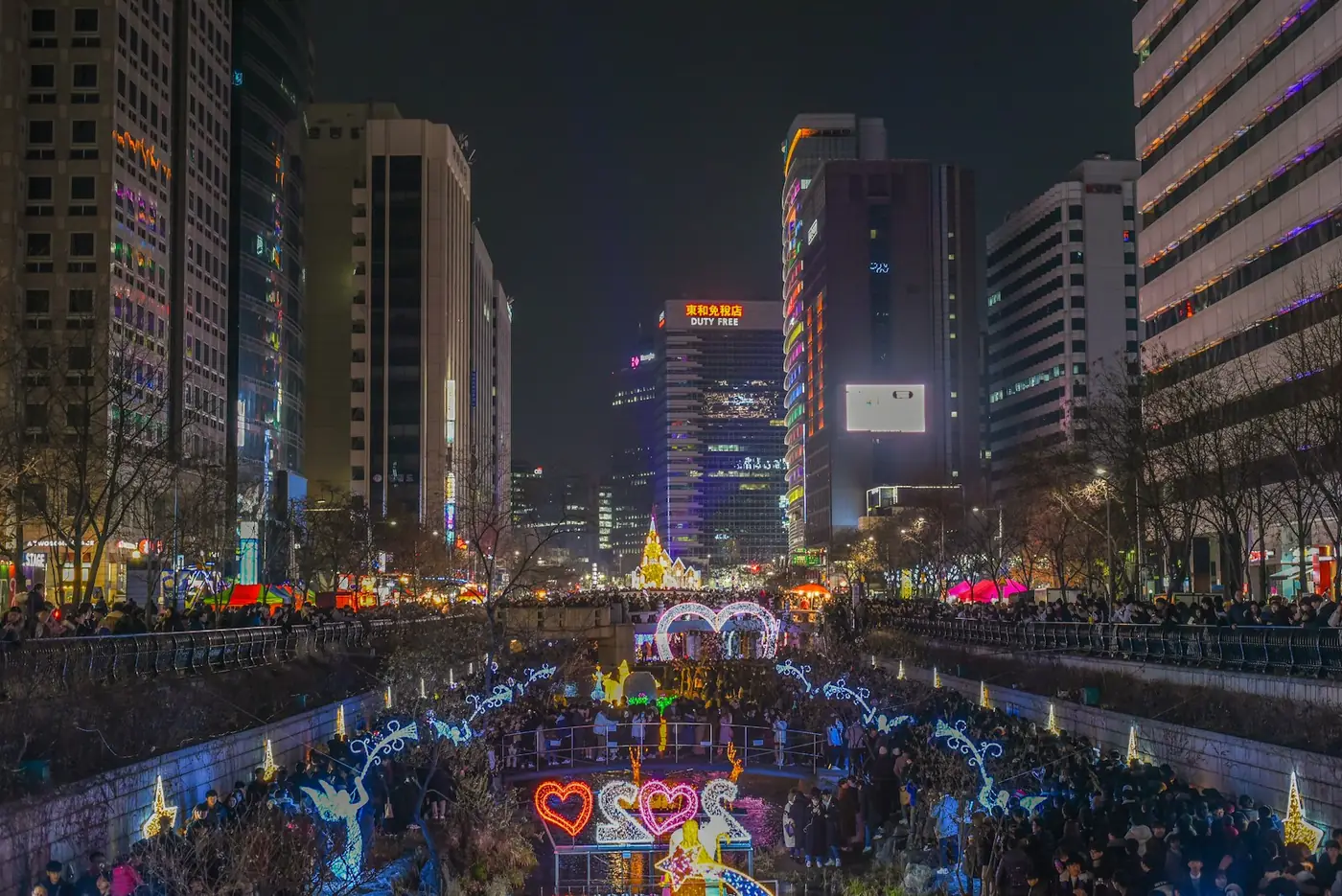 Crowds at a winter light festival lighting up a plaza between office towers in central Seoul, South Korea