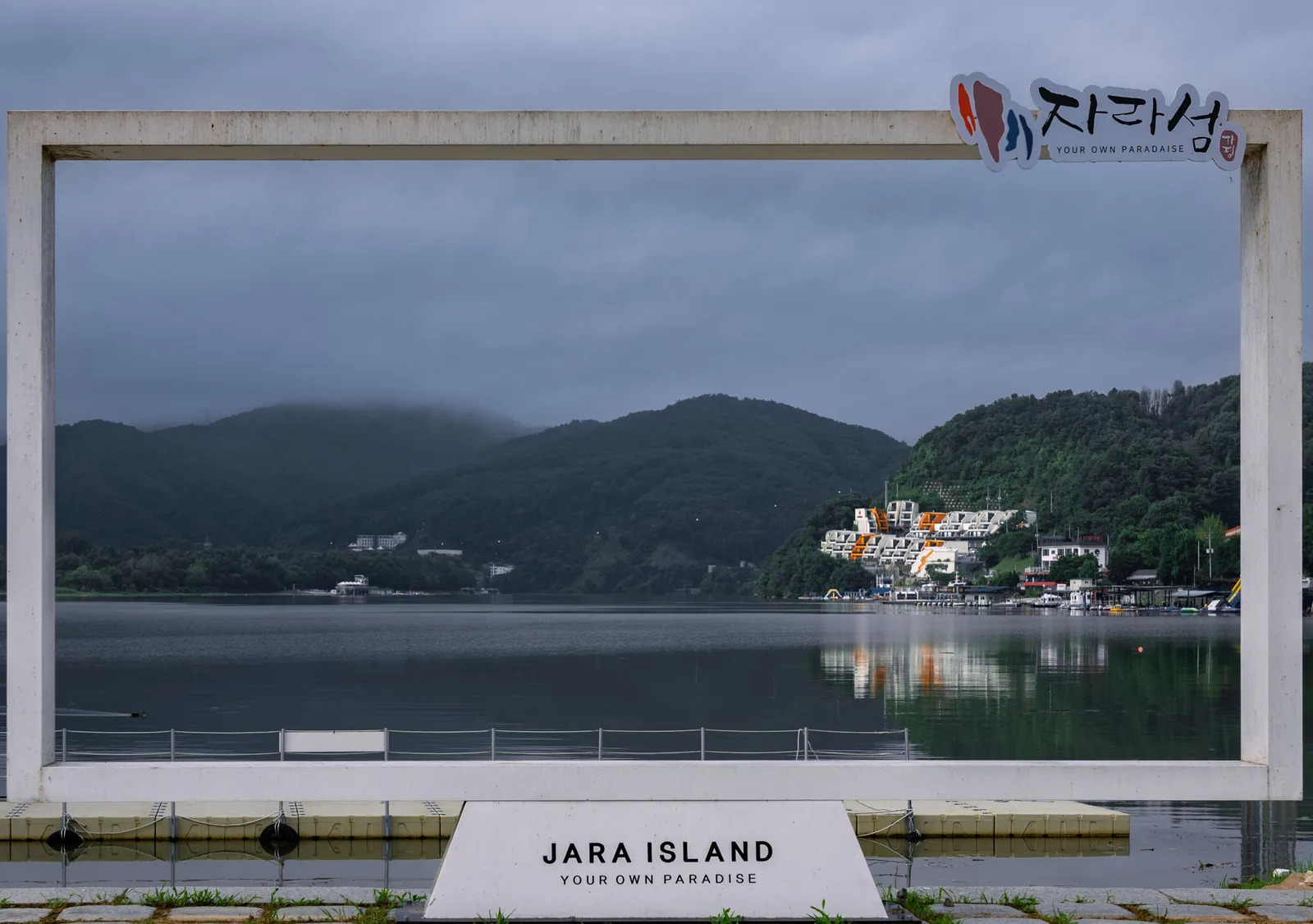 A signboard beside a lake with wooded hills behind near Gapyeong, South Korea