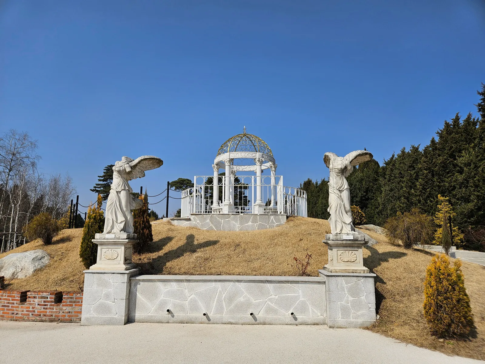 A white pavilion with statues on a landscaped hillside near Seoul, South Korea