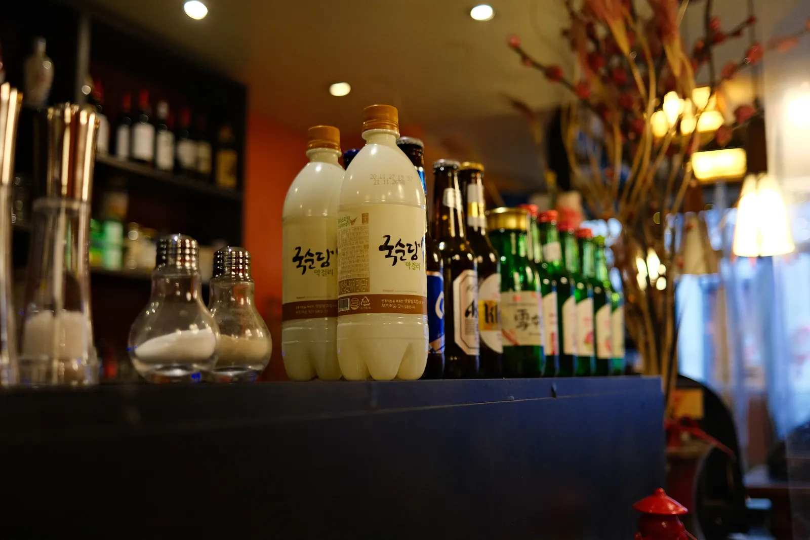 Bottles of makgeolli and soju lined up on a shelf behind a bar in Seoul