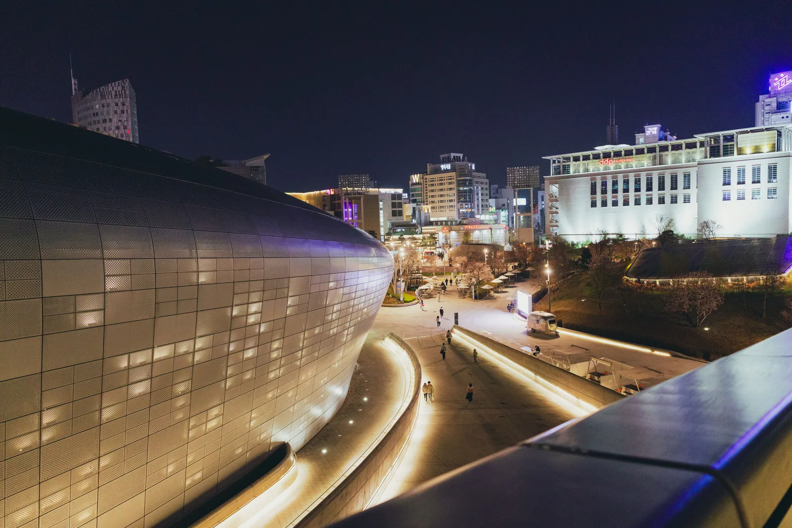 The curved metal facade of the Dongdaemun Design Plaza lit at night in Seoul, South Korea