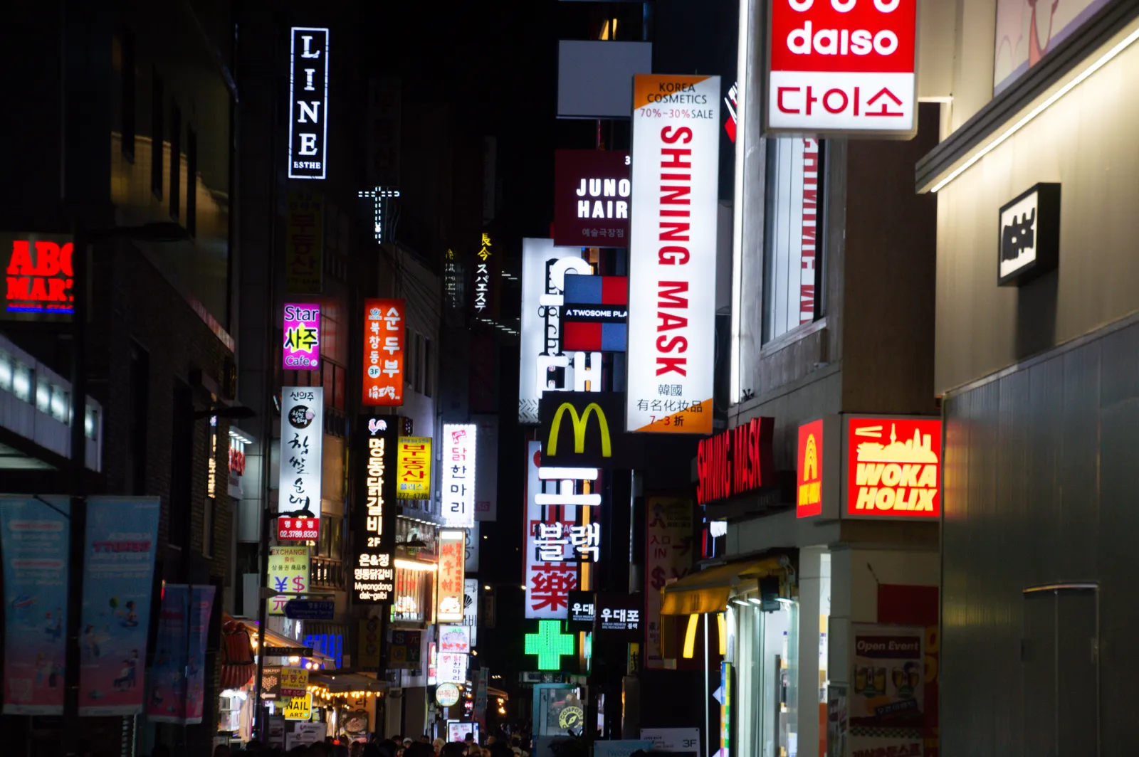A busy shopping street lined with cosmetics and chain store signs in Seoul, South Korea
