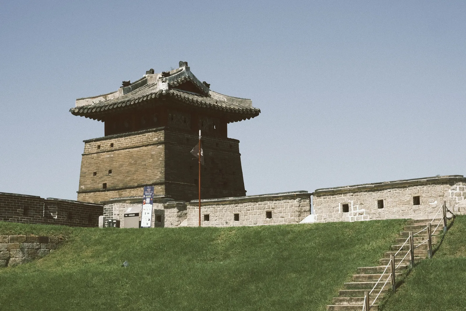 A stone bastion of the Hwaseong fortress wall under a clear sky in Suwon, South Korea