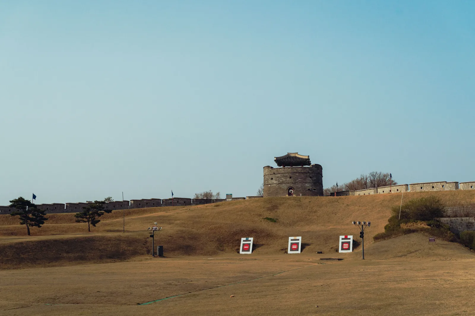 The fortress wall and a watchtower across open ground in Suwon, South Korea